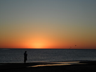 Naklejka na ściany i meble silhouette on the beach at sunset