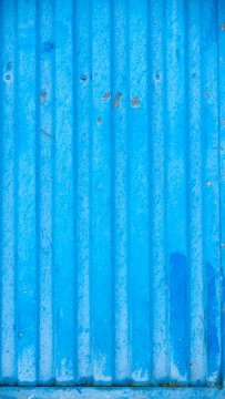 Puerta de metal corrugado pintada de azul deteriorada por el tiempo