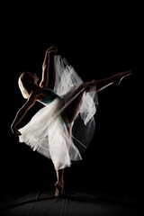 ballerina with a white dress and black top posing on black background