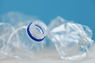 Clean empty crumpled plastic water bottles on blue background. Waste management and plastic reuse concept. Environmental contamination. Macro texture