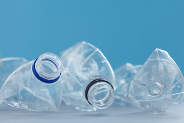 Clean empty crumpled plastic water bottles on blue background. Waste management and plastic reuse concept. Environmental contamination. Macro texture