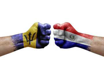 Two hands punch to each others on white background. Country flags painted fists, conflict crisis concept between barbados and paraguay