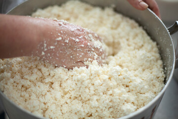 Cook mixes cottage cheese in pot. Hand kneads dairy products. Work in dining room. Details of...