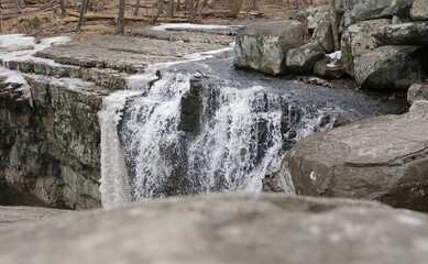Partially Frozen Waterfall Flowing over Boulders at Ringing Rock Park on Winter Day