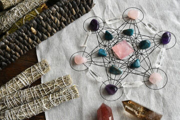 A top view image of a crystal healing grid with rose quartz pyramid and white sage.