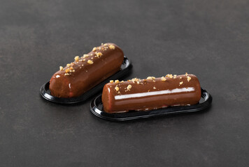 Chocolate walnut mousse cake in the shape of a bar with mirror glaze on a dark gray background. Close-up