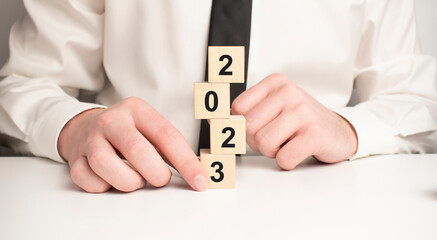 The word 2023. New year concept. Putting wood cubes with numbers and icons. Top view of wood table.
