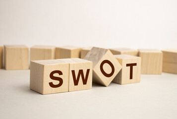 The word SWOT. Concept image of SWOT analysis in business management. Putting wood cubes with alphabets and icons. Top view of wood table.