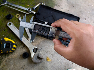 A technical engineer is holding a vernier caliper for support in measuring machine tools with high accuracy.