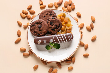 Plate with delicious chocolate cake, cookies and almonds on light background
