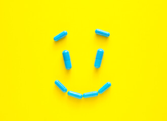 Smile made of blue pills on color background