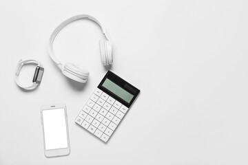 Mobile phone, smart watch, headphones and calculator on white background