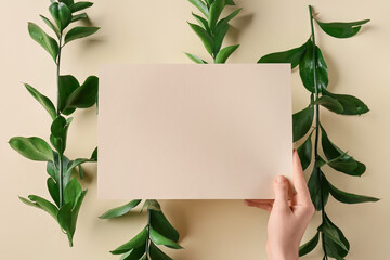 Female hand with blank card and plant branches on color background, closeup