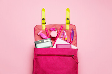 Stylish backpack with different stationery on pink background