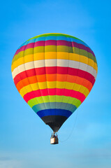Naklejka premium Beautiful colorful hot air balloon flying on the clear blue sky background.