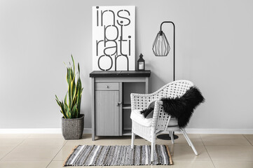 Stylish chest of drawers, picture, lamp and chair near grey wall in room