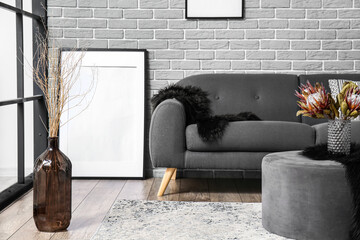 Stylish interior with grey sofa on brick wall background