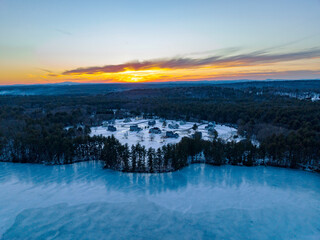 residential community in forest near frozen river under dusk sunlight