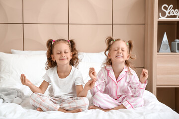 Adorable little girls meditating in bedroom - obrazy, fototapety, plakaty