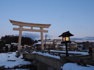 雪の積もる街の神社の鳥居と灯篭