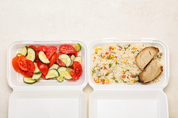 Fresh salad and rice with vegetables in lunch boxes on light background