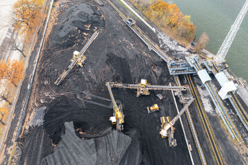 Territory of the coal terminal with coal dumps and a regenerator. loading and unloading of coal by excavators and belt conveyors. coal reserves at thermal power plants. View from above