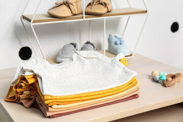 Stack of baby clothes on table near color wall