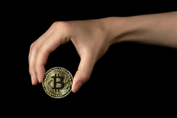 Plakat Woman's hand holds a bitcoin in her fingers. Isolated on black background