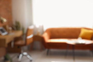 Blurred view of stylish living room with red sofa and workplace