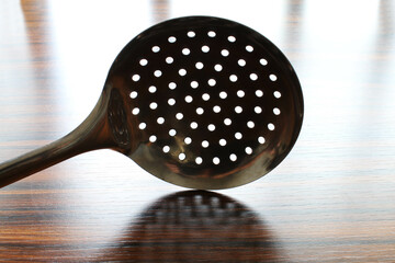 Scummer on the table under window light. Kitchen utensil.