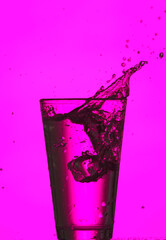 Glass of clear water with splash on color background