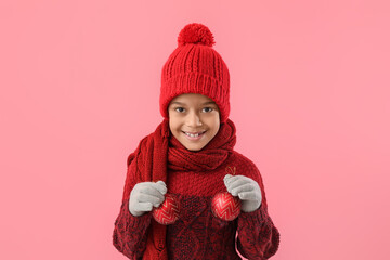 Cute little African-American boy in winter clothes and with Christmas balls on color background