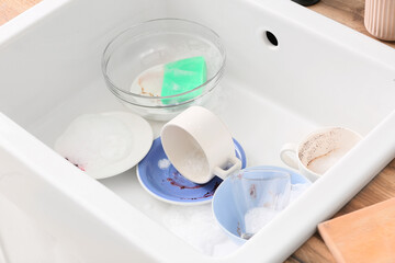 Dirty dishes in ceramic sink, closeup