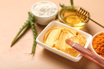 Bowls with turmeric mask, powder, makeup brush and honey on beige background, closeup