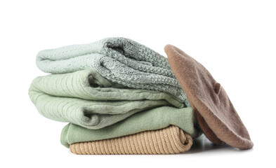 Stack of stylish sweaters and beret hat on white background