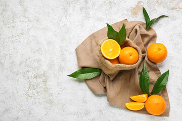 Sack with fresh juicy oranges on light background