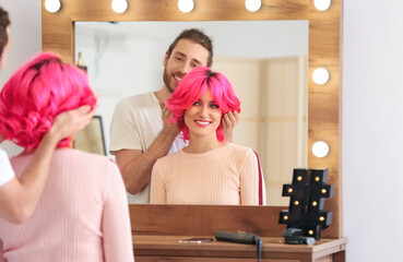 Male stylist doing hair of young woman in beauty salon