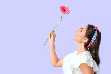 Woman looking at gerbera flower on violet background. International Women's Day