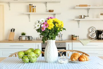 Vase with beautiful Chrysanthemum flowers on dining table in kitchen
