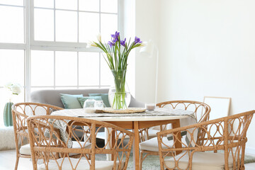 Vase with beautiful irises on dining table in room