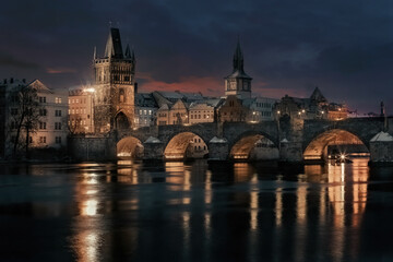 Fototapeta na wymiar Snowy old stone Charles Bridge on the Vltava river in winter in the evening in the center of Prague