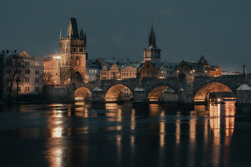 Fototapeta premium Snowy old stone Charles Bridge on the Vltava river in winter in the evening in the center of Prague