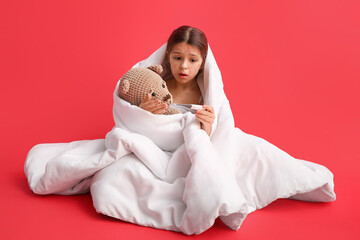 Little girl ill with chickenpox measuring temperature on red background