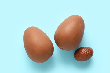 Tasty chocolate Easter eggs on blue background