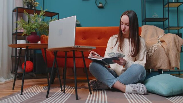 Young Woman Doing, Planning Home Budget And Counting Money, Girl Checking Dollar Cash To Pay Utility Bills. Young Lady Reviewing Invoices On Laptop Computer, Doing Family Business Plan And Tax Return