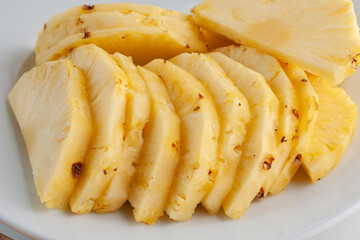Pineapple slices on a white plate as part of healthy foods concepts. Macro photohgraphy, side view.