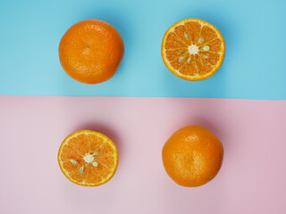 Creative concept made from oranges on blue and pink pastel background. healthy and minimal fruit concept