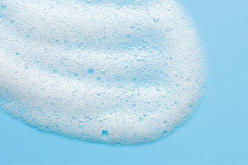 Cosmetic foam bubbles on blue background. Cleanser, face wach, hair shampoo soap suds texture. Abstract foamy cleansing product macro - obrazy, fototapety, plakaty