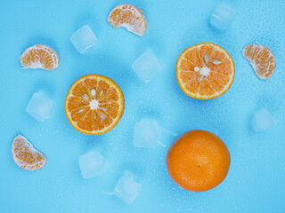 Creative summer pattern of oranges and ice cubes on blue pastel background. healthy and minimal fruit concept