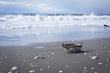 貝の散らばった砂浜に放置される錆びれた鍋